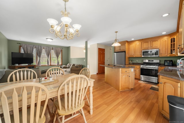 kitchen with an inviting chandelier, open floor plan, a center island, a sink, and stainless steel appliances