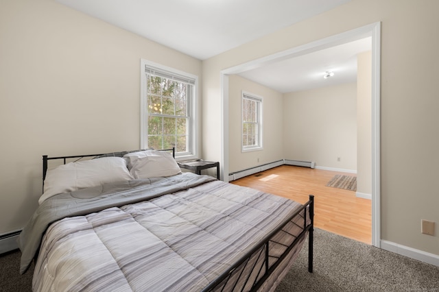 bedroom with baseboards, baseboard heating, and light wood-type flooring
