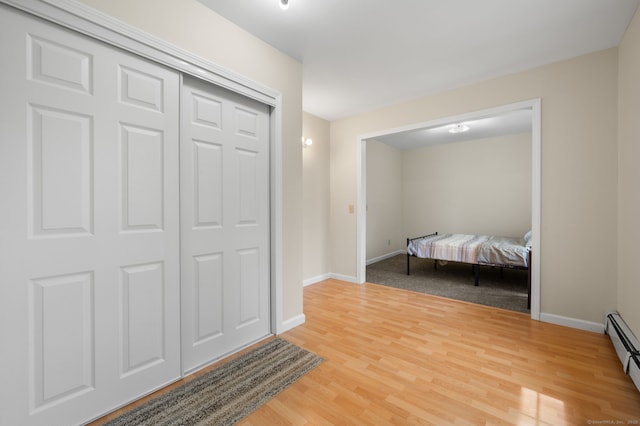 interior space with baseboards, a baseboard heating unit, and light wood finished floors