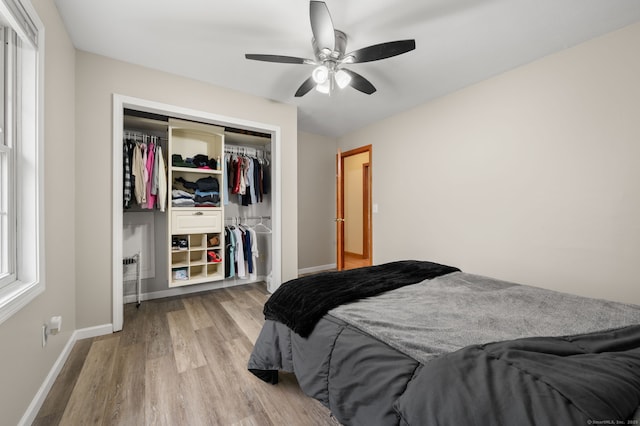 bedroom with a ceiling fan, baseboards, wood finished floors, and a closet