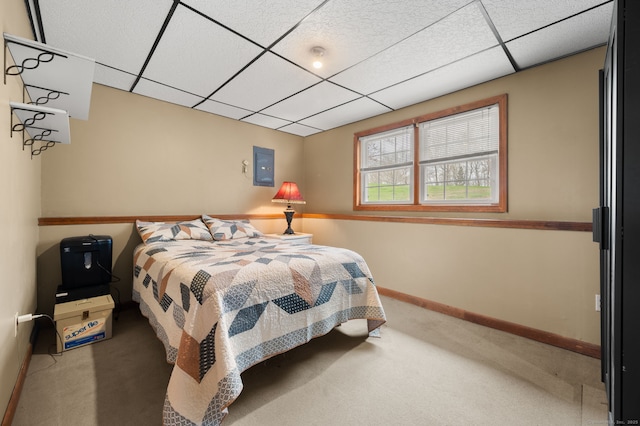 carpeted bedroom featuring baseboards and a drop ceiling