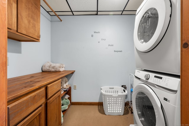 laundry area with baseboards, stacked washer and clothes dryer, and cabinet space