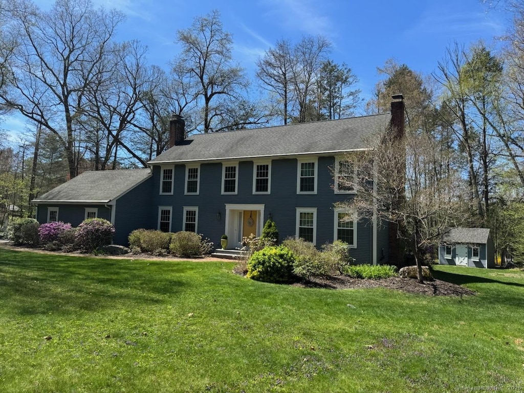 colonial-style house with a front lawn and a chimney