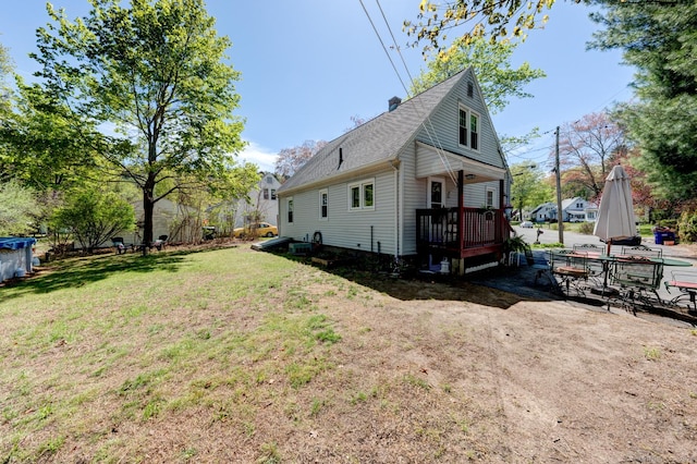 view of side of home featuring roof with shingles, a chimney, and a yard