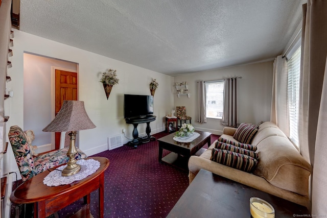 carpeted living room featuring baseboards, a textured ceiling, and visible vents