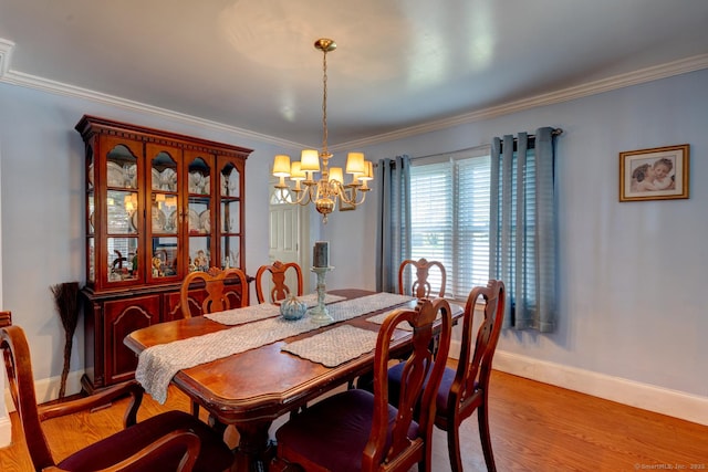 dining room featuring baseboards, ornamental molding, light wood finished floors, and a chandelier