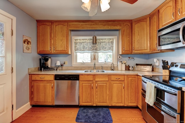 kitchen featuring a sink, light wood finished floors, light countertops, stainless steel appliances, and a ceiling fan