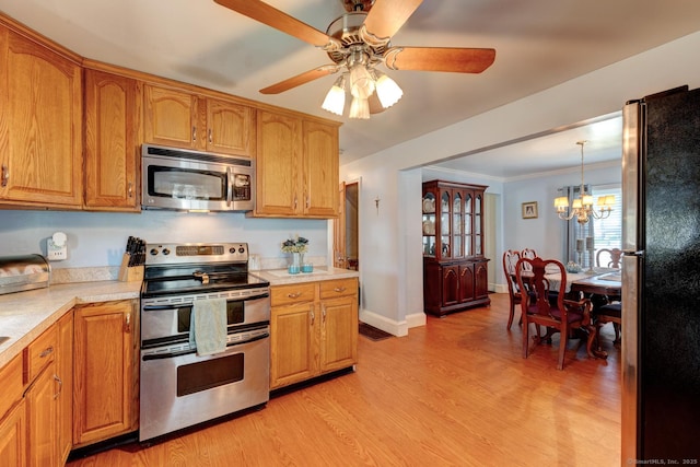 kitchen featuring light wood finished floors, light countertops, brown cabinetry, ceiling fan with notable chandelier, and stainless steel appliances