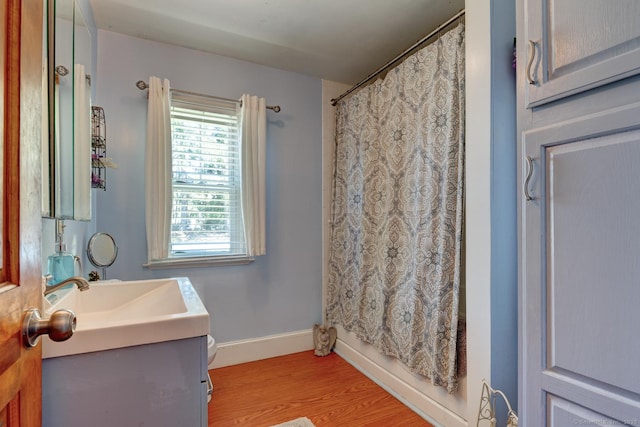 full bath featuring a shower with shower curtain, baseboards, wood finished floors, and vanity