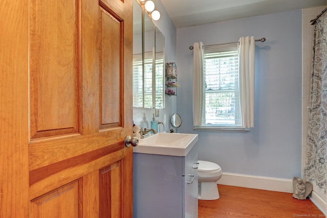 bathroom with baseboards, wood finished floors, toilet, and vanity