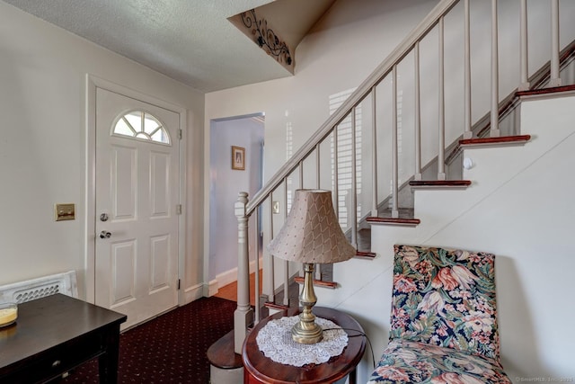 carpeted entrance foyer with stairs and a textured ceiling