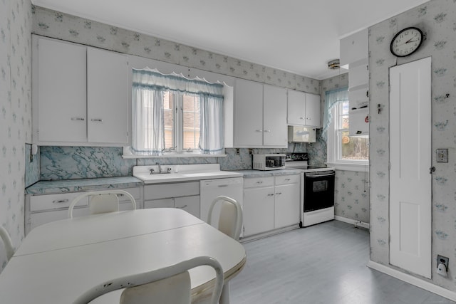 706 Ocean Ave, West Haven, CT 06516 - kitchen with white appliances, wallpapered walls, light wood-style floors, a sink, and white cabinets