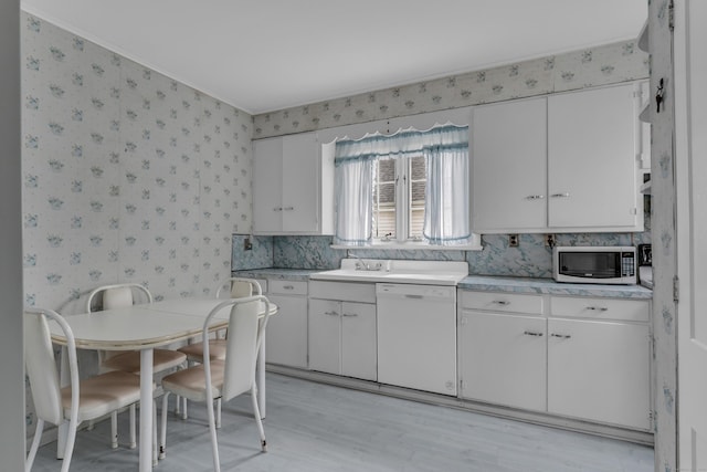 706 Ocean Ave, West Haven, CT 06516 - kitchen with dishwasher, wallpapered walls, light countertops, white cabinets, and light wood-type flooring