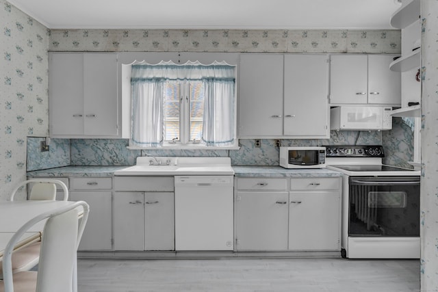 706 Ocean Ave, West Haven, CT 06516 - kitchen with white appliances, wallpapered walls, light countertops, a sink, and light wood-type flooring