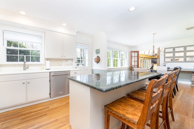 kitchen featuring an inviting chandelier, ornamental molding, a breakfast bar area, a sink, and dishwasher