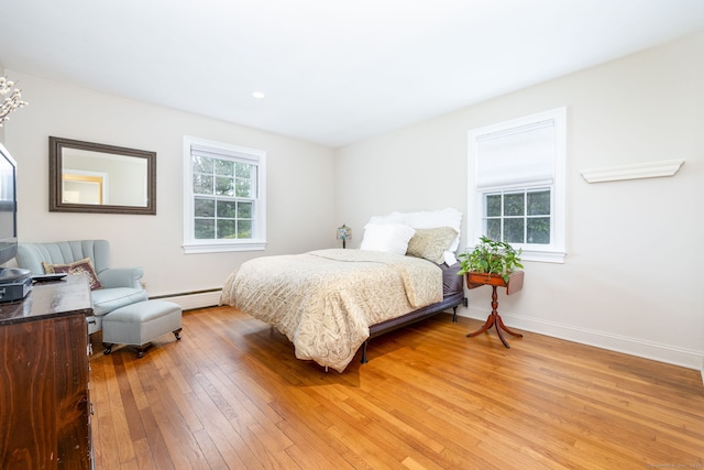 bedroom featuring baseboards, a baseboard heating unit, and light wood-type flooring
