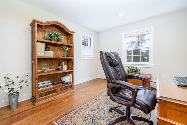 home office with baseboards, a baseboard heating unit, wood finished floors, and a wealth of natural light