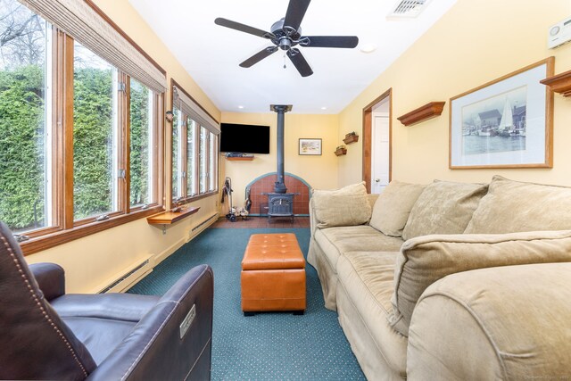 carpeted living room with a ceiling fan, baseboard heating, a wood stove, and visible vents