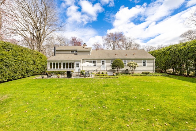 rear view of property with entry steps, a patio, a chimney, and a yard