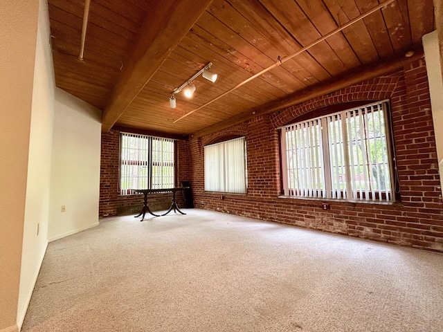 empty room featuring carpet, wooden ceiling, and brick wall
