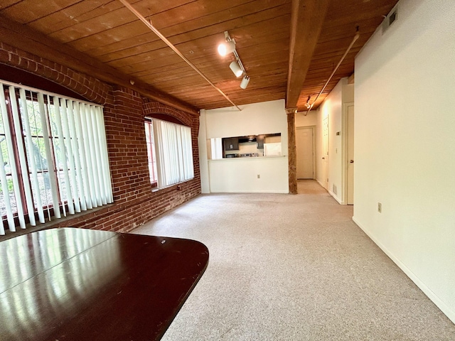 unfurnished living room featuring brick wall, rail lighting, wood ceiling, and carpet floors