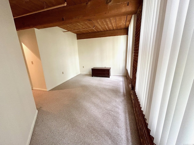 carpeted spare room featuring baseboards, beam ceiling, and wood ceiling