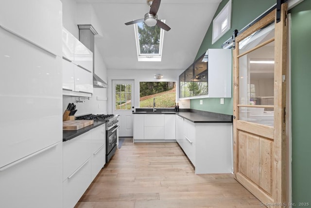kitchen with a ceiling fan, modern cabinets, stainless steel range, and dark countertops