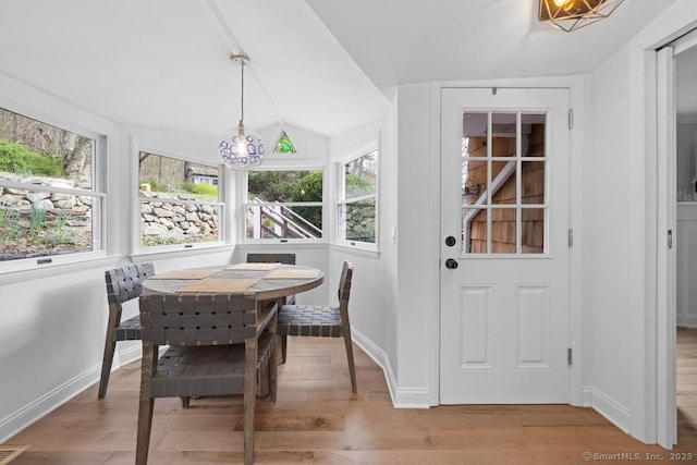 dining area featuring baseboards, light wood finished floors, lofted ceiling, and a notable chandelier