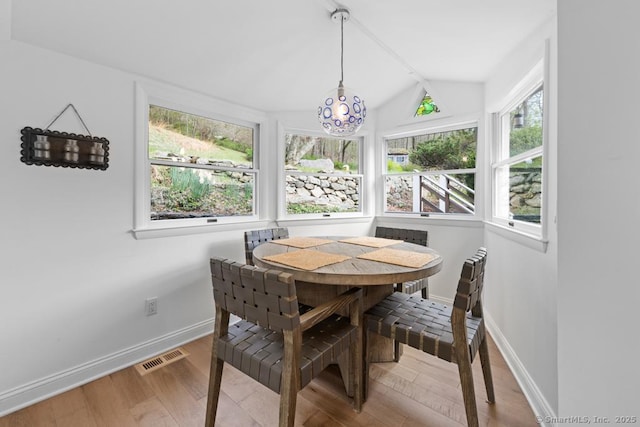 dining space featuring baseboards, vaulted ceiling with beams, wood finished floors, and visible vents