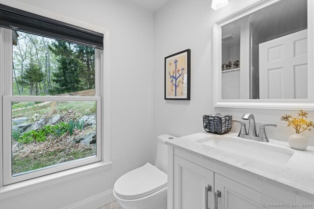 bathroom with plenty of natural light, toilet, and vanity