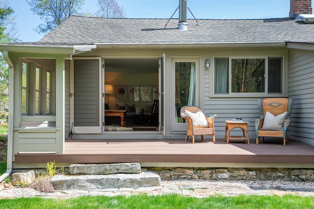 back of property featuring a chimney, roof with shingles, and a deck