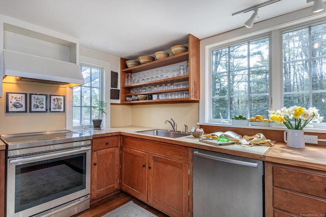 kitchen featuring open shelves, wood finished floors, light countertops, a sink, and stainless steel appliances