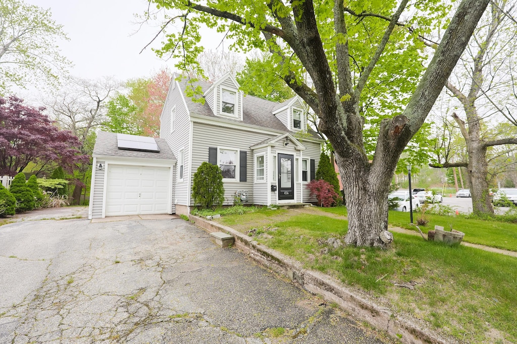 456 Painter Dr, West Haven, CT 06516 - cape cod home with roof mounted solar panels, driveway, a garage, and a front lawn