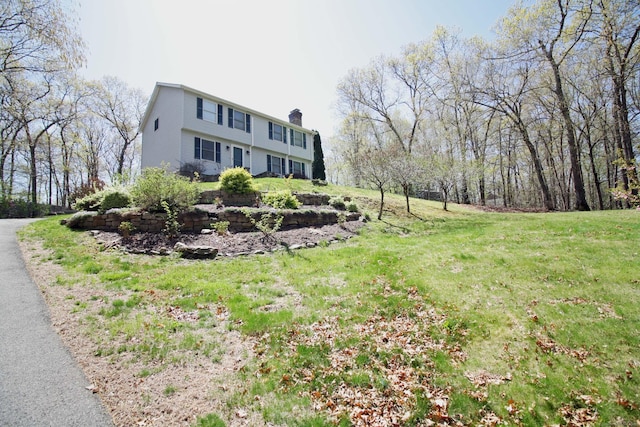 view of front of house featuring a chimney and a front yard