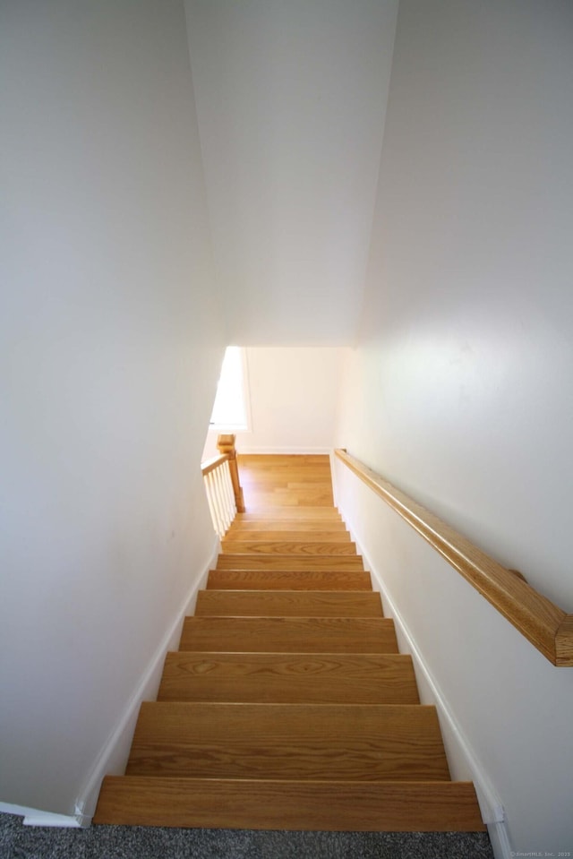 staircase with baseboards and wood finished floors