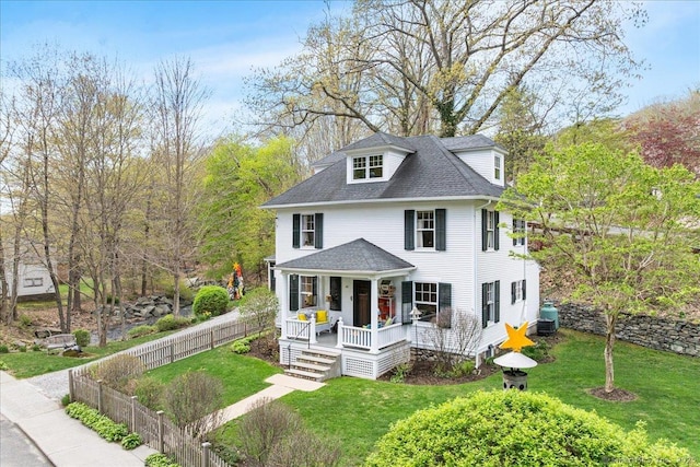 traditional style home with a porch, a shingled roof, fence, and a front yard