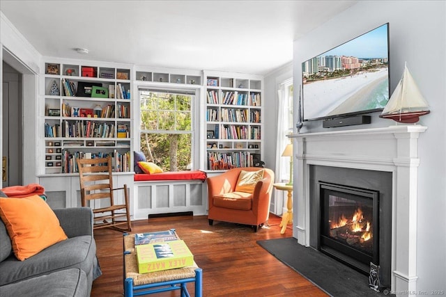 sitting room featuring a glass covered fireplace, built in features, and wood finished floors
