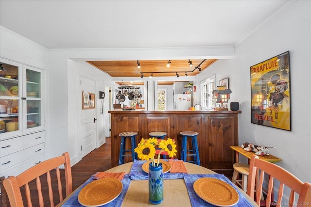 dining area featuring a bar, ornamental molding, and wood finished floors