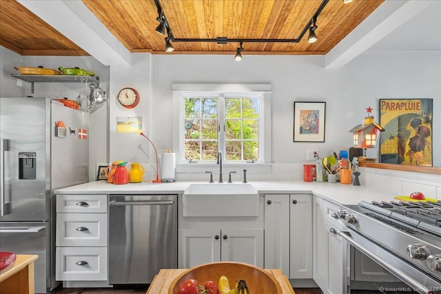 kitchen with a sink, wood ceiling, stainless steel appliances, and rail lighting