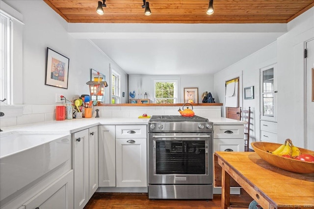 kitchen featuring a peninsula, light countertops, white cabinets, dark wood finished floors, and stainless steel range