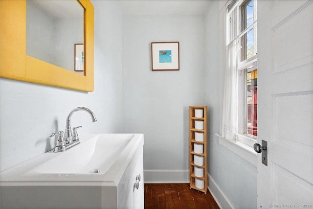 bathroom featuring baseboards, a sink, and wood finished floors