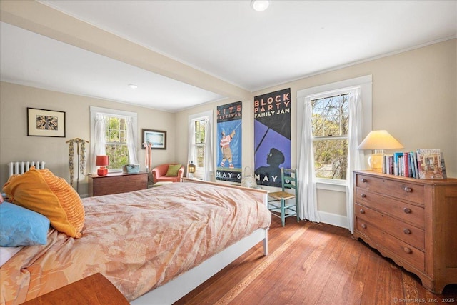 bedroom featuring wood-type flooring, recessed lighting, baseboards, and radiator heating unit