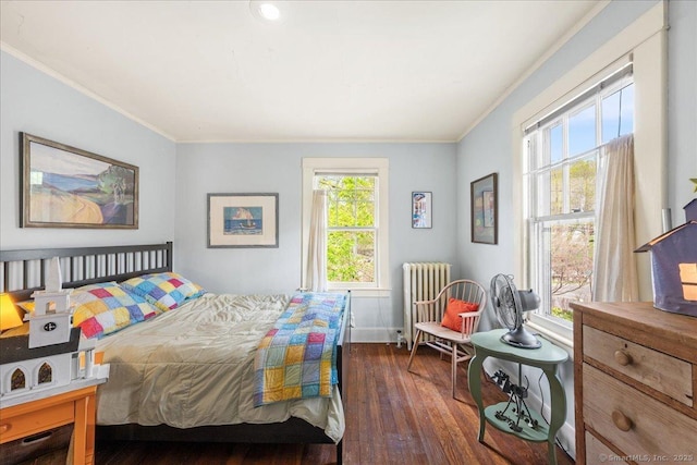bedroom with radiator, ornamental molding, baseboards, and wood finished floors
