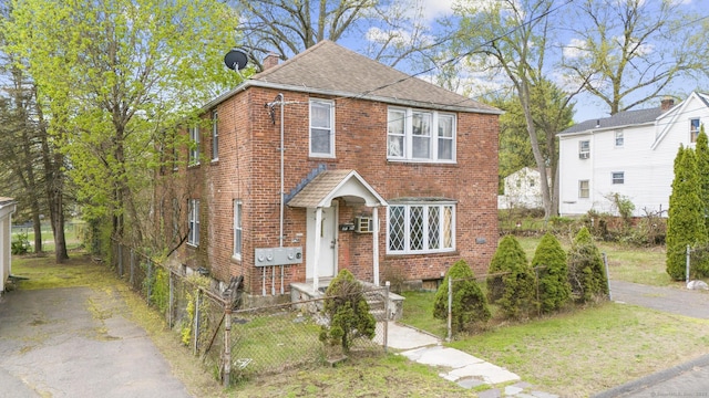 view of front facade with brick siding, a shingled roof, a chimney, and fence private yard