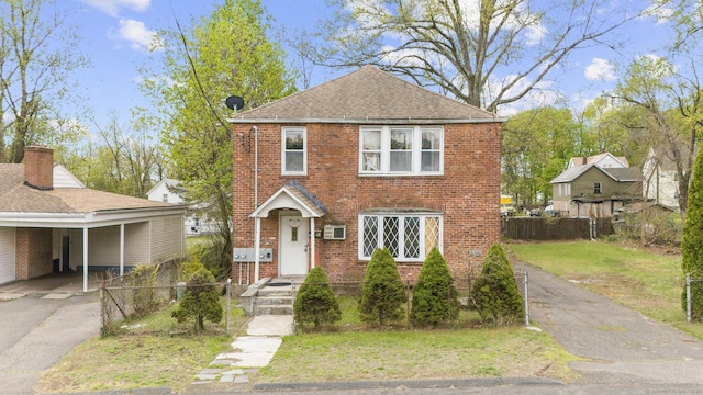 view of front of home with brick siding, fence, driveway, and a front yard
