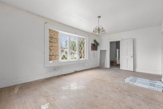 unfurnished dining area with an inviting chandelier and hardwood / wood-style floors