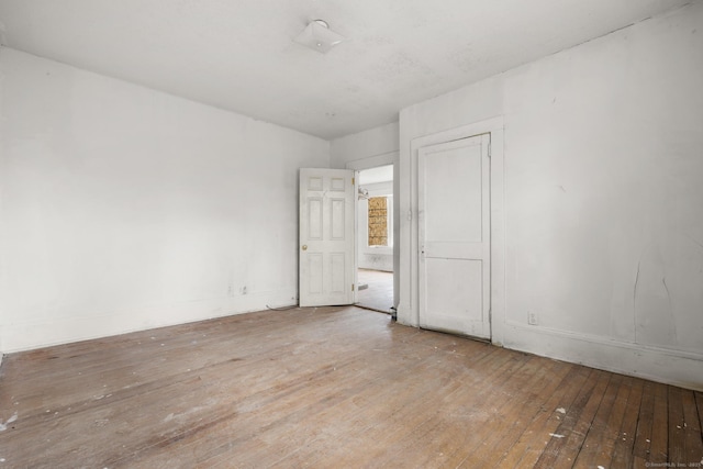spare room with baseboards and hardwood / wood-style floors