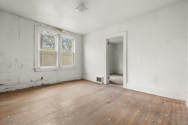 unfurnished bedroom featuring wood-type flooring, a textured ceiling, baseboards, and visible vents