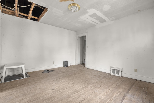 unfurnished room with baseboards, wood finished floors, and visible vents