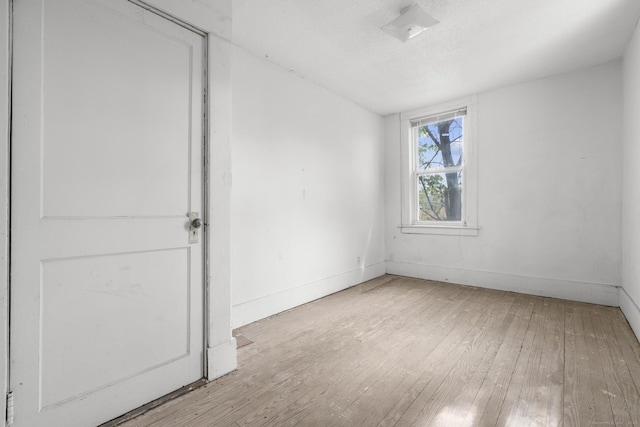 unfurnished room with baseboards and hardwood / wood-style flooring